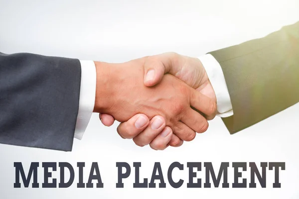 Conceptual caption Media Placement. Business concept the method of placing your ad message using the media Two Professional Well-Dressed Corporate Businessmen Handshake Indoors