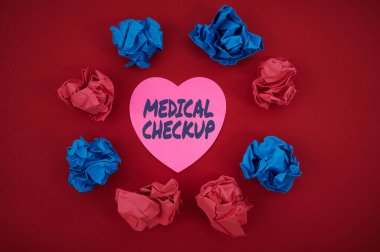 Kavramsal manşet Tıbbi Kontrol. Konsept, genel sağlık durumunuzu test etmek için tıbbi muayene anlamına geliyor. Renkli Buruşuk kağıtlar, yuvarlak şekilli kalp şeklindeki kağıt..