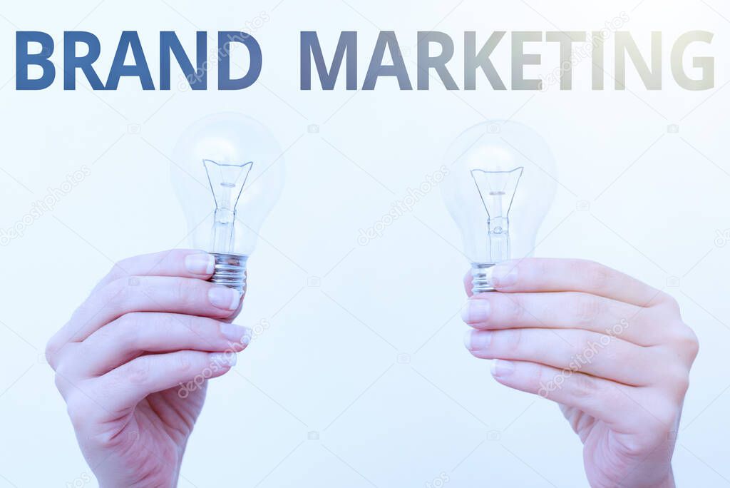 Writing displaying text Brand Marketing. Business showcase creating a name that identifies and differentiates a product two Hands holding lamp showing or presenting new technology ideas
