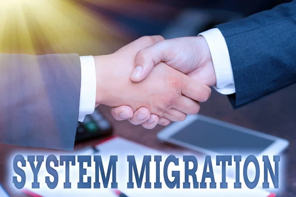 Hand writing sign System Migration. Business overview moving from the use of one operating environment to another Two Professional Well-Dressed Corporate Businessmen Handshake Indoors