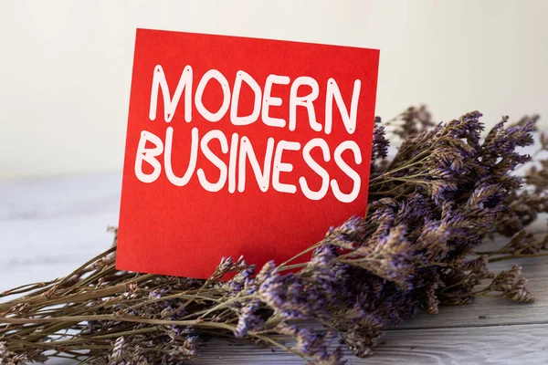 Signo de texto que muestra Modern Business. Concepto que significa sistema económico donde se intercambian bienes y servicios Pieza en blanco de nota adhesiva colocada en la parte superior de una mesa al lado de una planta. — Foto de Stock