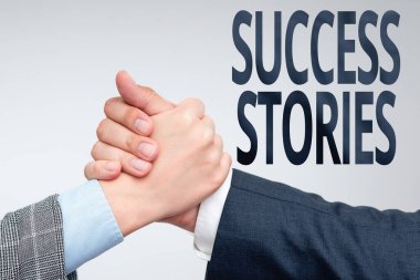 Başarı Öyküleri 'ni gösteren metin işareti. Büyük başarı elde eden bir şeyin ya da birinin iş dünyası hikayesi. İki profesyonel iyi giyimli iş adamı kapalı mekanda el sıkışıyor.