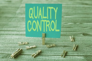 El yazısı Kalite Kontrolü. Yeni Fikir Gösteren Çamaşır Klipleriyle çevrelenmiş Boş Kare Notunun Standartları nedeniyle satılan ürün veya servisin iş konsepti.