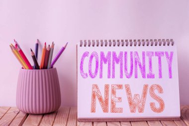 Kavramsal manşet Community News. Tipik olarak şehir mahallelerine odaklanan haberler için kelime Boş Spiral Not Defteri Masadaki Renkli Kalemler Yığını.