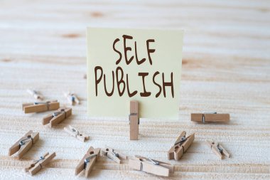 Self Publish 'i gösteren bir tabela. Kavram demek, yazar kendi harcamalarıyla bağımsız olarak çalışan bir parçanın yayınlanması anlamına gelir. Yeni Anlamı Gösteren Çamaşır Klipleri ile çevrelenmiş Boş Kare Notu.