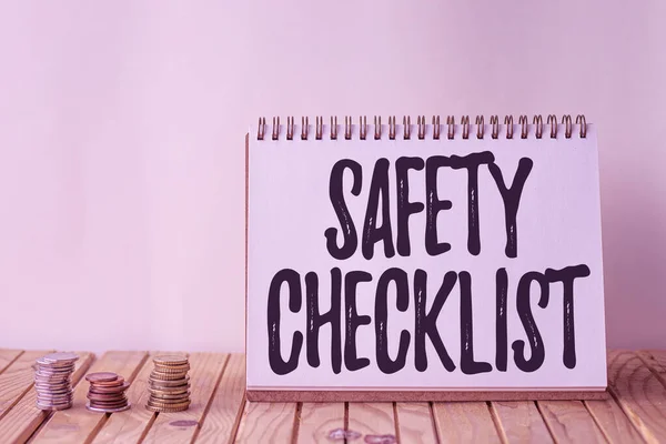 Text caption presenting Safety Checklist. Word for list of items you need to verify, check or inspect Empty Open Spiral Notebook Beside Stockpile Of Coins On Top Of Desk.