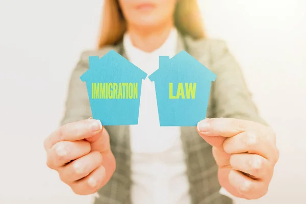 Texto mostrando inspiração Lei de Imigração. Conceito significado Emigração de um cidadão deve ser legal na tomada de viagens Uma mulher de negócios Jovem Segurando Apresentando Casa Em Roupa de Negócios — Fotografia de Stock