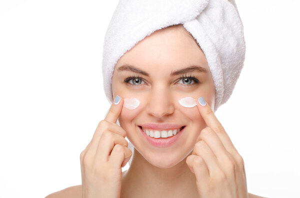 Красивая молодая женщина наносит крем на лицо изолированы на белом фоне
