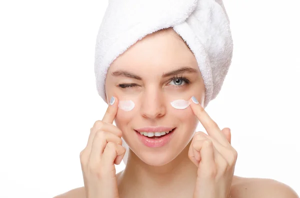 Bella giovane donna che applica una crema sul suo viso isolato su sfondo bianco — Foto Stock