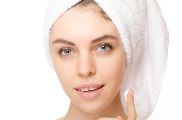 Mooie jonge vrouw toepassing van een crème op haar gezicht geïsoleerd op witte achtergrond — Stockfoto
