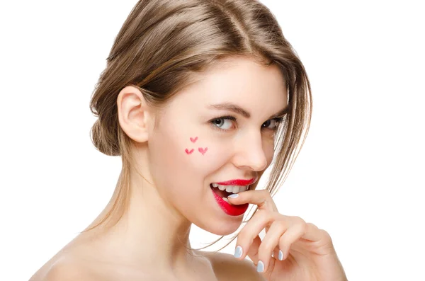 Chica modelo de belleza con maquillaje perfecto mirando a la cámara aislada sobre blanco con labios rojos y pequeños corazones en la mejilla —  Fotos de Stock