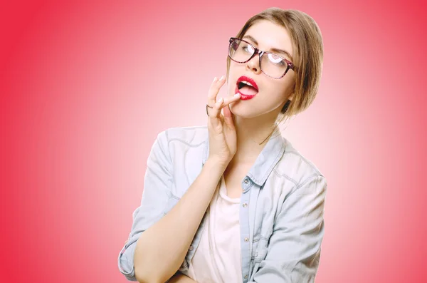 Hermosa joven con la piel perfecta en gafas sobre un fondo rojo — Foto de Stock