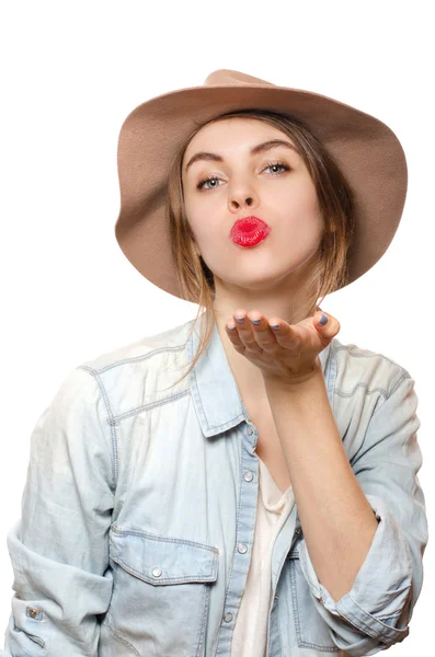 Joven mujer sexy enviando un beso con labios rojos en la pared blanca, usando sombrero, mostrar emociones felices — Foto de Stock