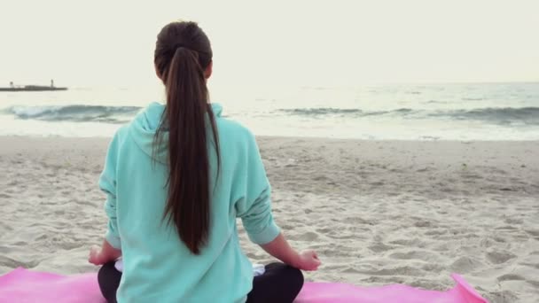 Atraktivní žena v józe představují meditaci na pláži