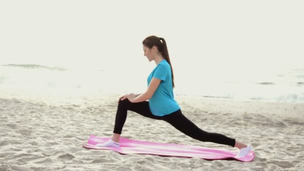 Νεαρή γυναίκα που κάνει άσκηση γιόγκα στην παραλία το καλοκαίρι άμμο με την Ανατολή — Αρχείο Βίντεο