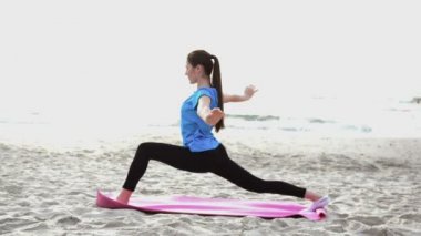 Genç kadın yaz kum plaj üzerinde günbatımında germe yoga egzersiz yaparak