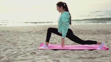 Genç kadın deniz kenarında kumsalda Yoga uygulamak