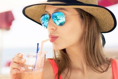 Güverte onun kokteyl beach club tutan sandalyede oturan kadın