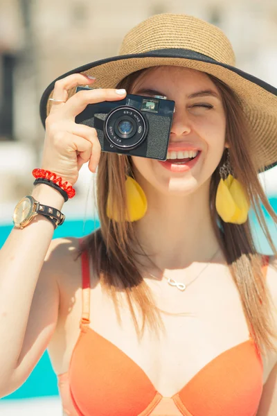 Девушка в бикини на пляже делает фото с кинокамерой — стоковое фото