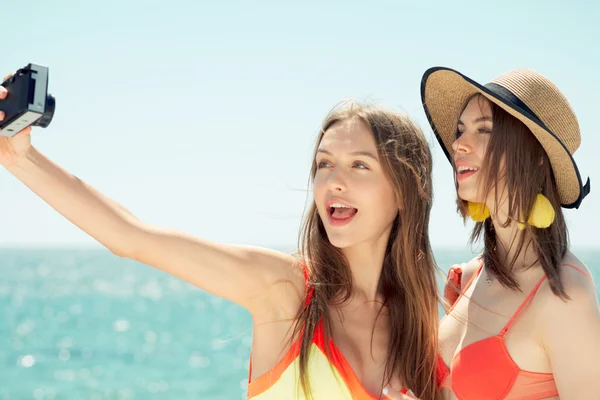 Dwa uśmiechnięte młode kobiety na plaży co selfie — Zdjęcie stockowe