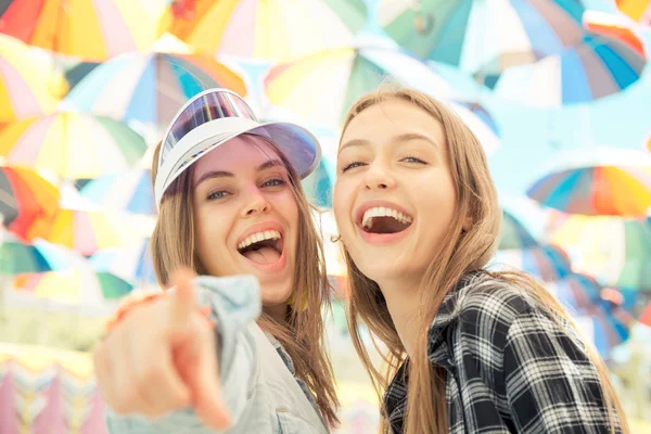 Mujeres jóvenes felices caminando al aire libre con un fondo moderno de sombrillas —  Fotos de Stock