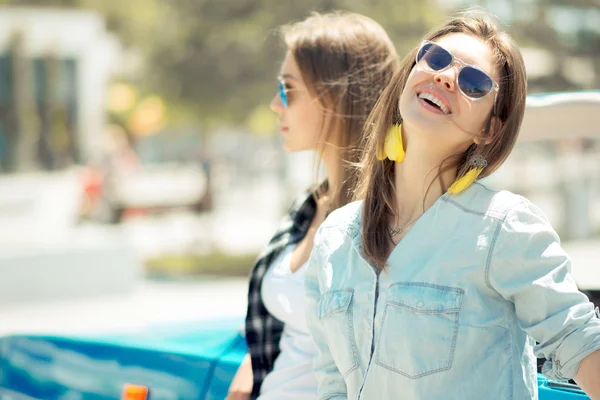 Красивые дамы в солнцезащитных очках позируют возле винтажной кабриолеты — стоковое фото