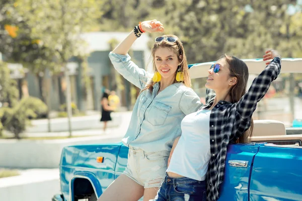 Красиві дами в сонцезахисних окулярах позують біля старовинної кабіни автомобіля — стокове фото