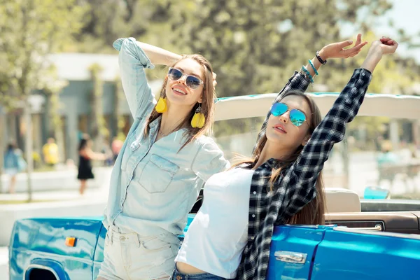 Senhoras bonitas em óculos de sol posando perto do carro vintage cabriole — Fotografia de Stock