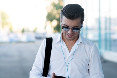 yakışıklı genç adam akıllı telefon ve kulaklık ile müzik dinlemek