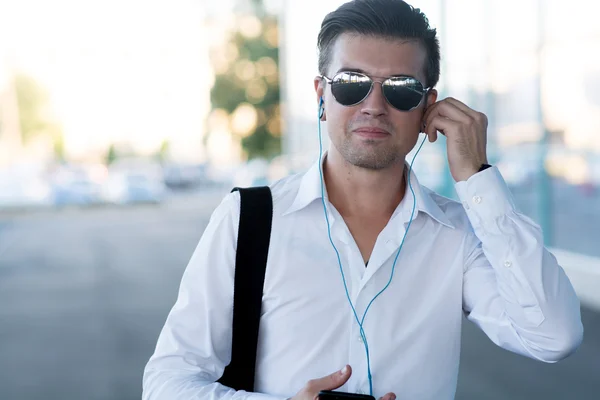 Joven guapo con teléfono inteligente y auriculares escuchar música — Foto de Stock