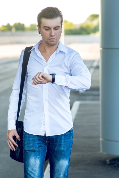 Joven hombre con estilo en un apuro mirando su reloj — Foto de Stock