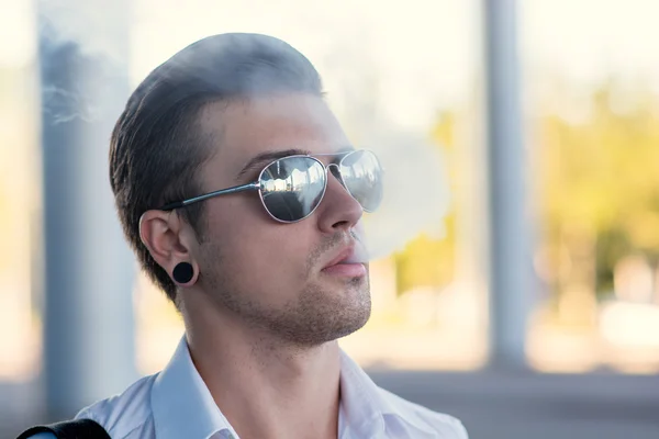 Hombre joven fumando cigarrillo electrónico al aire libre — Foto de Stock