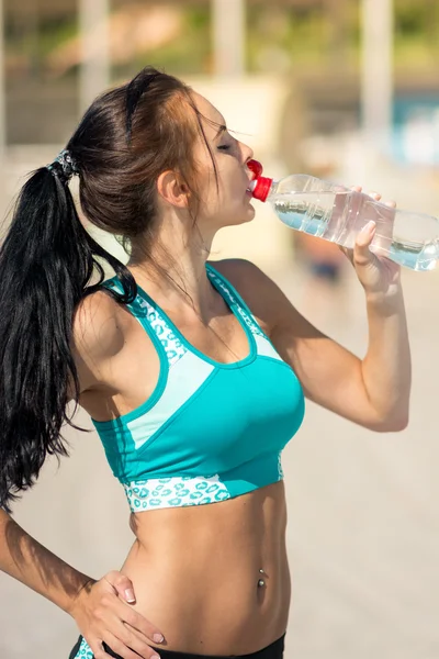 Fitness woman drinking water after running at beach — Stock Photo, Image