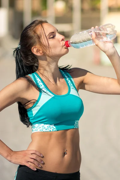 Fitness woman drinking water after running at beach — Stock Photo, Image