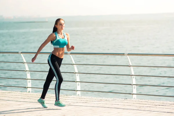 Молода жінка в літньому спортивному одязі біжить уздовж пляжу — стокове фото