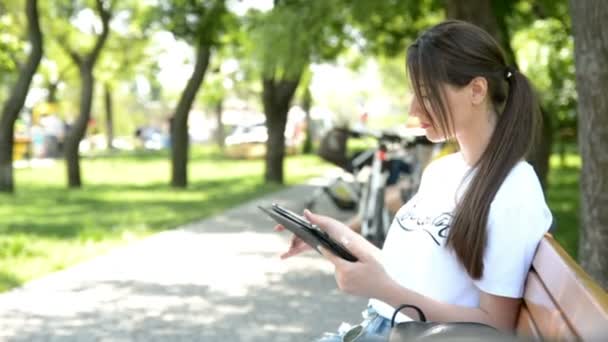 Glückliche junge Frau beendet Arbeit mit Tablet-Computer im Stadtpark — Stockvideo