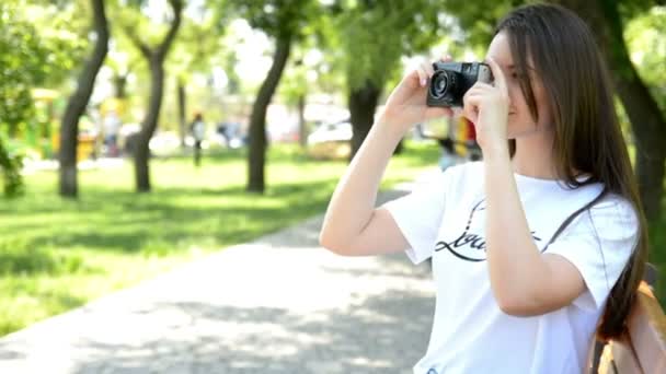 Jonge vrouw maken van foto's met vintage filmcamera in zomer groen park. — Stockvideo