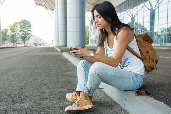 Fiatal, csinos nő ül a smartphone, látszik a hallgatása — Stock Fotó