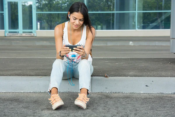 Joven bonita mujer sentada con teléfono inteligente escuchar el musi — Foto de Stock