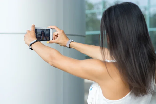 Mujer sonriente tomando una foto selfie en una calle urbana — Foto de Stock