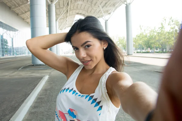 Gülümseyen kadın bir kenar mahallede selfie çekiyor.