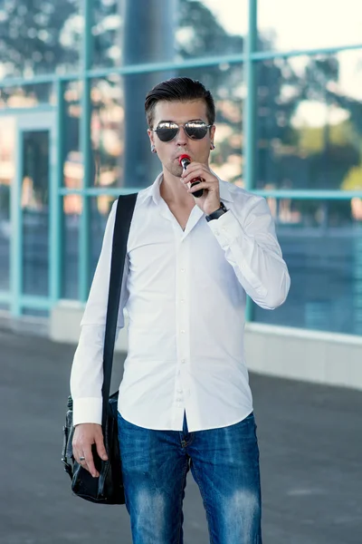Hombre joven fumando cigarrillo electrónico al aire libre — Foto de Stock