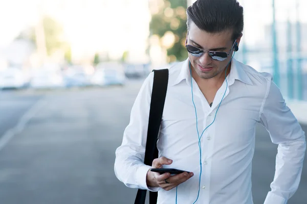 Csinos, fiatal férfi-a smartphone és a fejhallgató figyelj zene — Stock Fotó