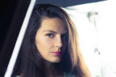 Üzgün genç kadın kamera ışık ile arka plan üzerinde arıyor.