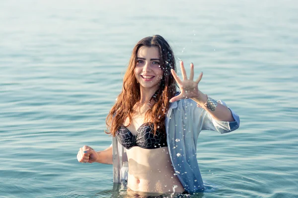 Bella ragazza spruzzando l'acqua nel mare — Foto Stock