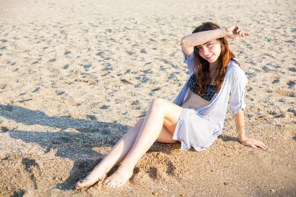 Привлекательная брюнетка позирует сидя на пляже — стоковое фото