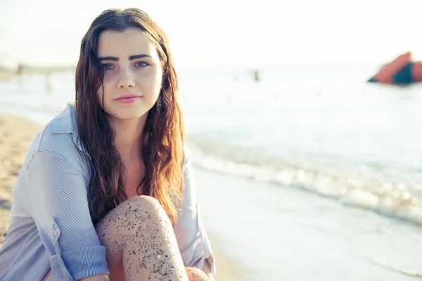 Jovem mulher pensativa na praia olhando câmera — Fotografia de Stock