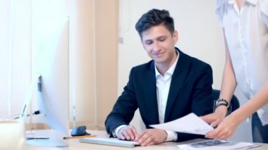 Sekreter erkek patronuna belgeler getiriyor. Bir adam bilgileri denetler