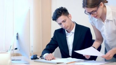 Sekreter erkek patronuna belgeler getiriyor. Bir adam bilgileri denetler