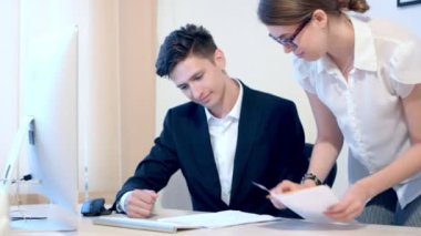 Sekreter erkek patronuna belgeler getiriyor. Bir adam bilgileri denetler